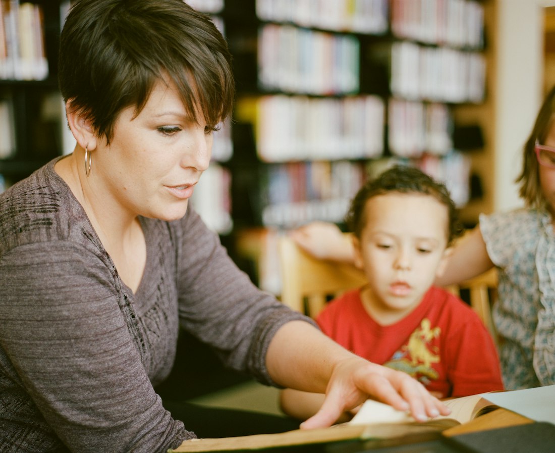 A teacher standing among library shelves