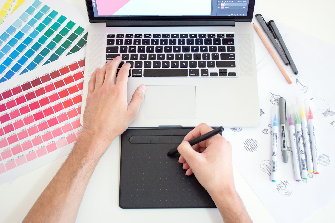 A designer sketching layout ideas on paper beside a pencil